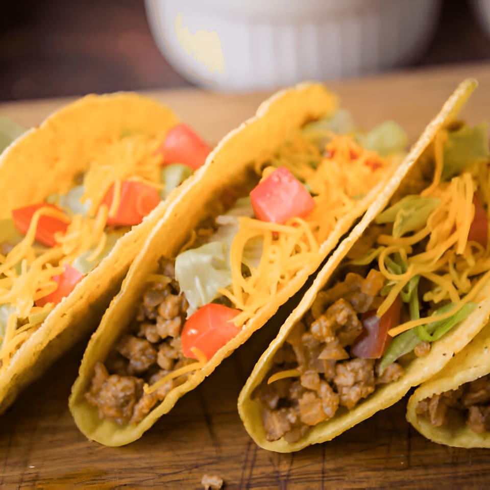 Four La Parrilla Fresh Mexican Bar & Grill tacos with meat, cheese, lettuce, and tomatoes.