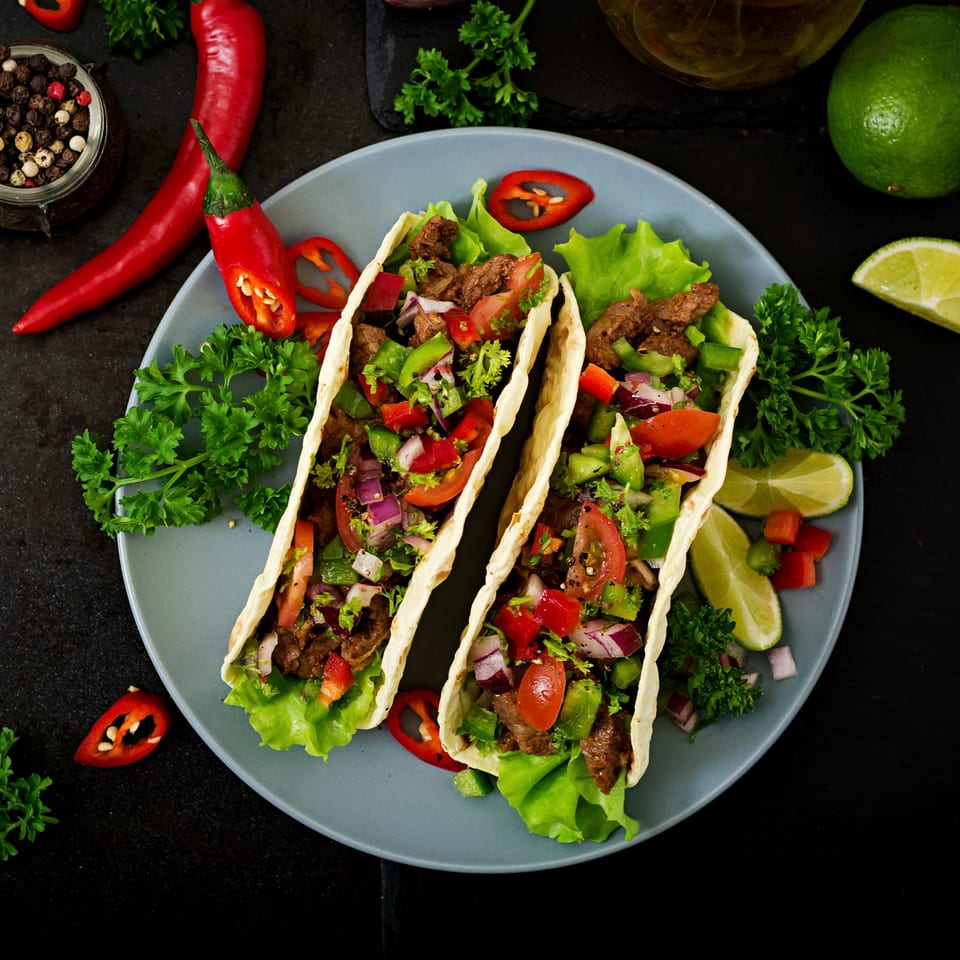 Two La Parrilla Fresh Mexican Bar & Grill tacos filled with meat, lettuce, and salsa.
